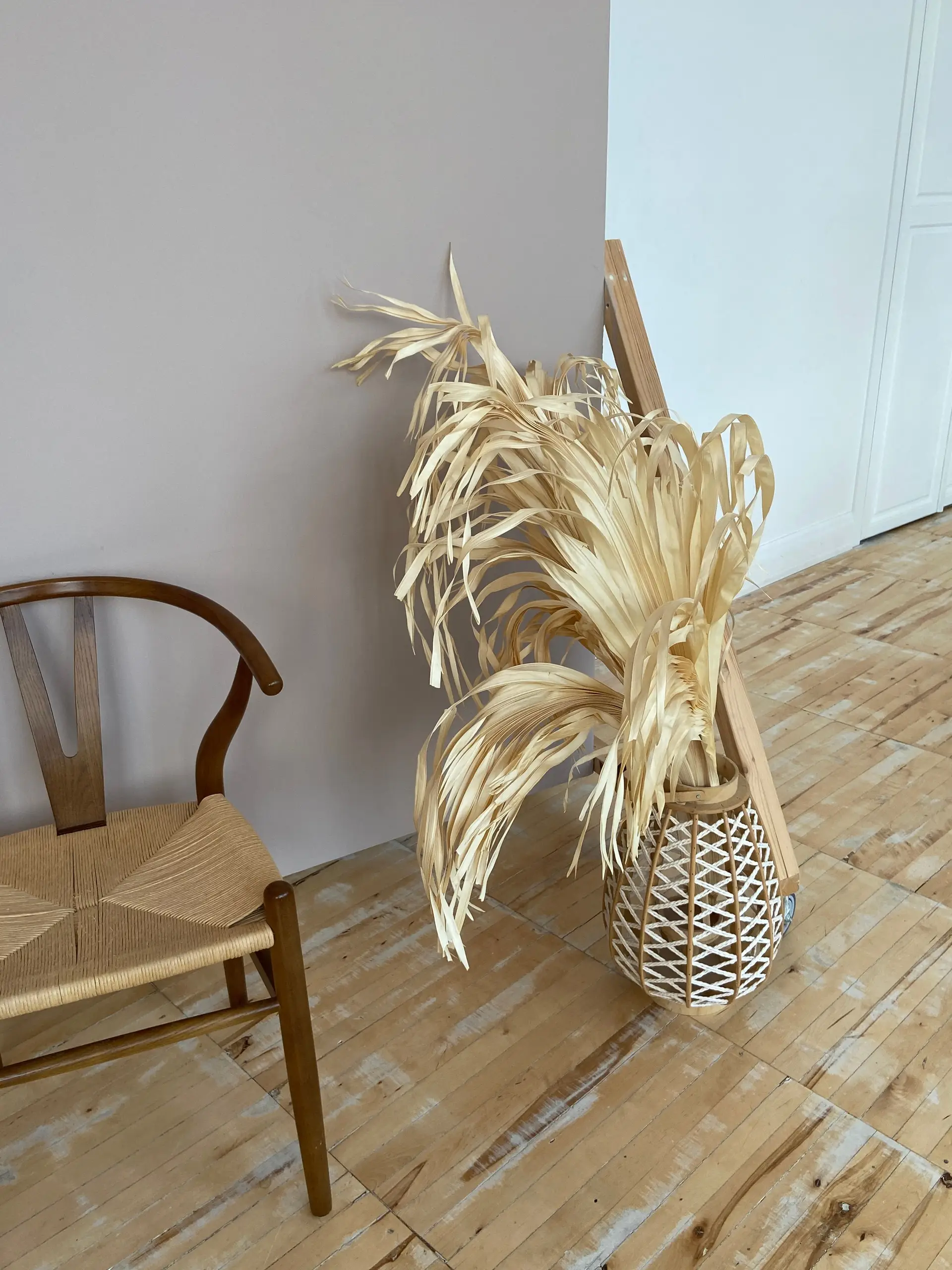 Detail of warm timber chair and dried botanical arrangement in woven vessel